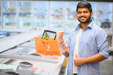 Smiling indian man choosing frozen meat in supermarket