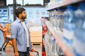 Indian man choosing bottled water in supermarket