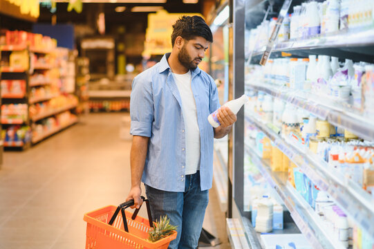 Indian man choosing milk bottle in supermarket refrigerator