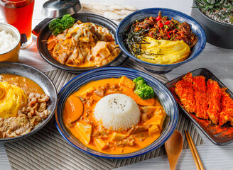 Assortment of Asian Rice Bowls Coconut Red Curry Rice, Crispy Fried Chicken, Stir-fried Pork, Pork Rice Bowl, Kimchi, Fluffy Scrambled Eggs and ice tea side veiw
