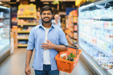 Indian man holding shopping basket in grocery store