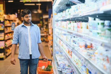 Young indian man choosing groceries in supermarket