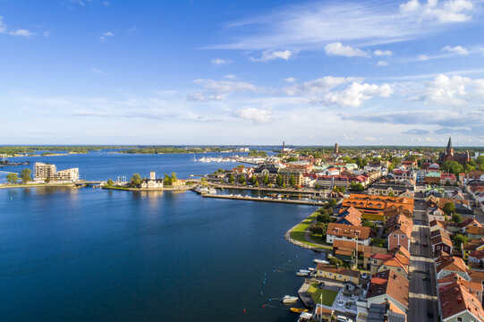 Aerial view of the town meeting the sea, bridges connecting islands under a vast sky, the blue waters contrasting with the red rooftops, Vastervik, Kalmar County, Sweden.