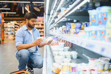 Customer choosing yogurt in dairy products section of supermarket