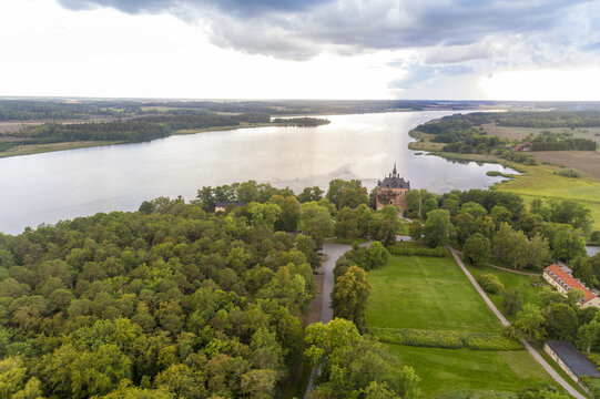 Aerial view of Wiks slott bathed in the soft glow of late afternoon sun, framed by the tranquil waters and lush forests, Wiks slott, Uppsala, Sweden.