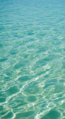 Clear turquoise water surface texture with gentle ripples and light reflections, suggesting serenity, peace, and summer vacation