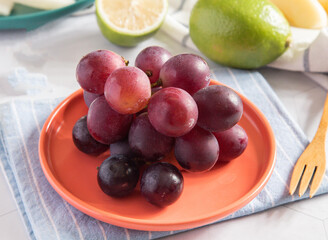 Fresh Red Grapes on a Plate with Lime and Wooden Fork side view of healthy fruit