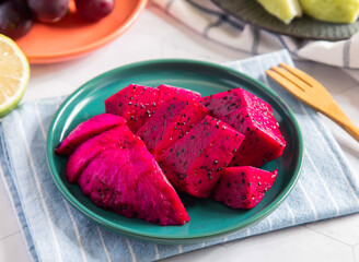 Vibrant Pink Pitaya Slices on a Plate with a Wooden Fork side view of healthy food snack