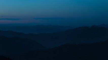 Fototapeta premium Silhouetted mountain range under a blue twilight sky, capturing a panoramic natural landscape.