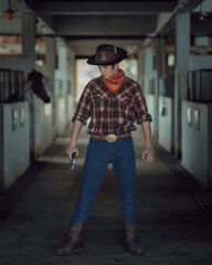 Handsome young country man in cowboy style and a gun for protection. Concept beautiful fashion...