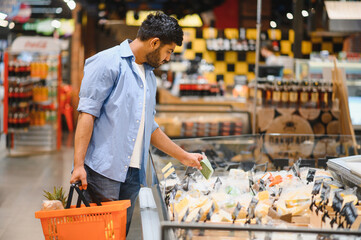 Customer choosing cheese in grocery store refrigerated display