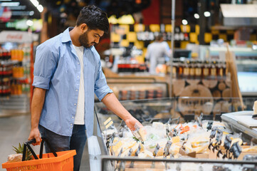 Young indian man choosing cheese in a supermarket