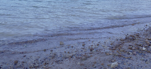 Close up of gentle waves washing over pebbles and sand on a calm shoreline creating a peaceful nature background
