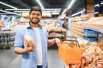 Smiling indian man shopping for bread and pineapple in supermarket