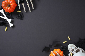 Spooky Halloween flat lay composition with pumpkins, skull, skeletal hands, bones, worms, bats, and...