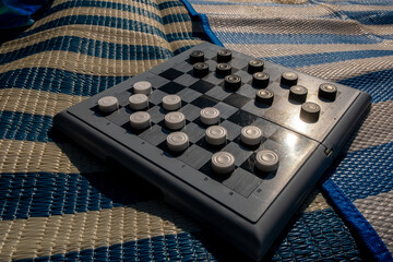A classic checkers game board displayed on a vibrant and colorful blanket outdoors