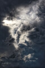 A dramatic, moody sky with a large, dark cloud formation, from which a bright ray of sun breaks...