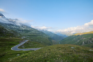 Scenic mountain roadway winding through lush valleys under a clear sky