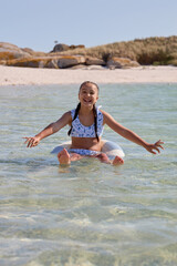Girl enjoying a sunny day in shallow water while sitting on a float in a clear coastal area