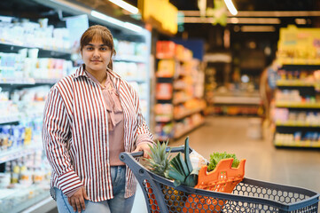 Indian woman pushing shopping cart in grocery store