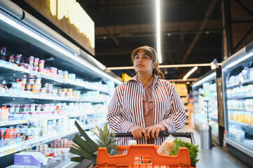 Indian woman choosing groceries in supermarket refrigerated aisle