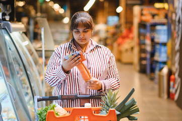 Customer reading product label while grocery shopping in supermarket