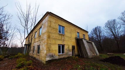 Abandoned building in rural area surrounded by trees on a cloudy afternoon