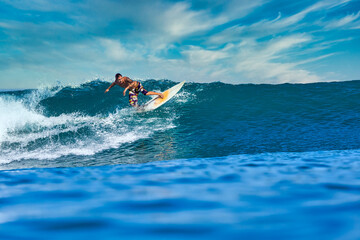 Male surfer on a blue wave at sunny day