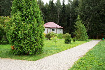 Cozy house nestled among trees in a tranquil natural setting with manicured lawns and a path on a...