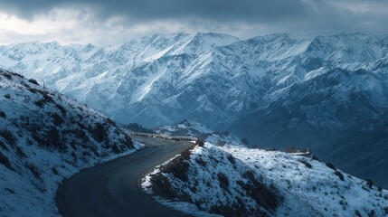 Winding road through snow-covered mountains at winter sunset showcasing nature's beauty and tranquility in remote areas