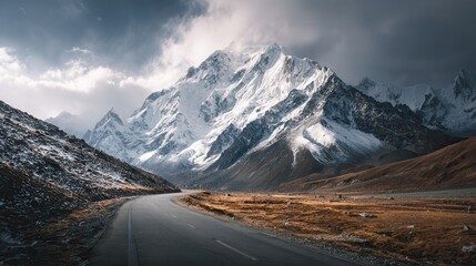 Fototapeta premium Winding road through snow-covered mountains at winter sunset showcasing nature's beauty and tranquility in remote areas
