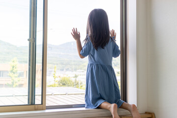 窓から外を見る女の子の後ろ姿（日本人、5歳）