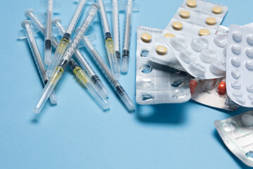 Assorted blister packs of various medications including tablets and capsules on a light blue...