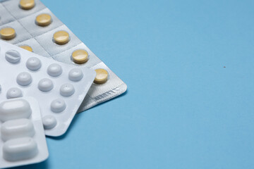 Assorted blister packs of various medications including tablets and capsules on a light blue...