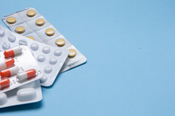 Assorted blister packs of various medications including tablets and capsules on a light blue...