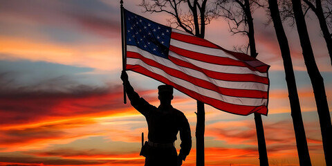 Silhouette of soldier holding american flag against a vibrant sunset sky with trees in the background