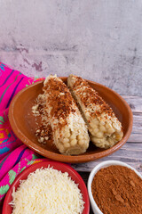 Mexican food. A pair of corn cobs prepared on a table near cheese and spicy chili peppers.