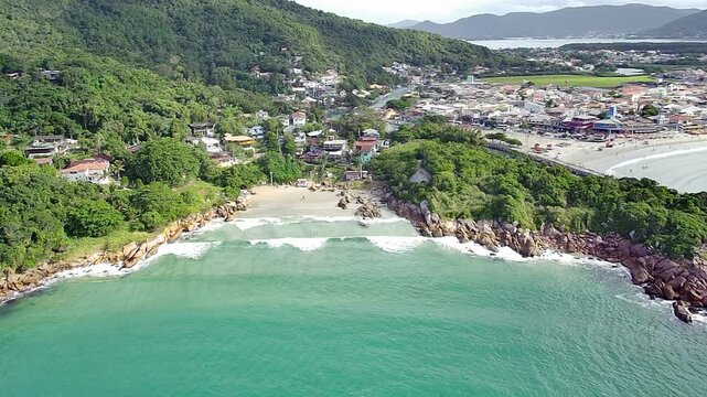 Aerial drone view of Barra da Lagoa Beach in Florian&oacute;polis, Brazil. The image captures the famous Canal da Barra, a small beach cove, and a coastal village nestled in lush Atlantic Forest hills.
