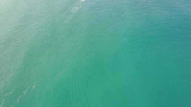 Aerial view of a boat wake on the turquoise ocean at Cachada&ccedil;o Beach (Praia do Cachada&ccedil;o) in Trindade, Rio de Janeiro, Brazil. Scenic seascape with natural pools and Trindade Island nearby.