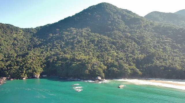 Aerial drone view of the stunning Cachada&ccedil;o Beach (Praia do Cachada&ccedil;o) in Trindade, Rio de Janeiro. The coastline features clear turquoise sea, natural pools, and lush Atlantic Forest hills.