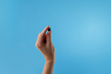 Hand holding SD card on blue background useful for tech startups, digital marketing agencies, app developers, IT support services, online education platforms, tech-related editorial content