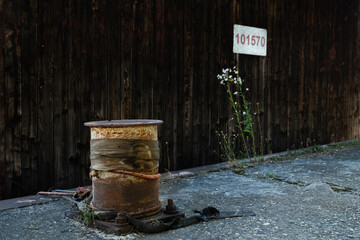 Weathered rusty bollard and wildflowers beside an old industrial dock infrastructure on a sunny day