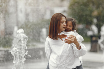 Mom and her little daughter playing by the spray of water