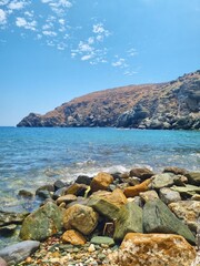Vertical view of the rocky beach and turquoise waters of Sifnos Island, Greece, with clear Aegean Sea and bright summer sky – a natural coastal landscape for travel