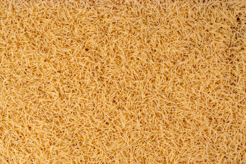 Raw vermicelli forming a dense layer showing off its texture and golden color, perfect for food-related backgrounds and culinary projects,