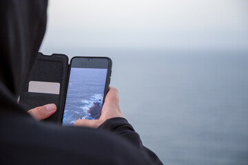 Persona che fotografa il mare usando uno smartphone