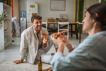 Couple enjoying pizza and beer at home