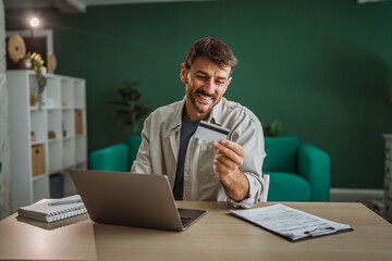Happy entrepreneur making online payment using credit card and laptop