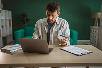 Focused entrepreneur making online payment using credit card and laptop