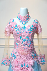 Elegant pink and turquoise wedding gown with intricate floral lace embroidery, sheer sleeves, and...
